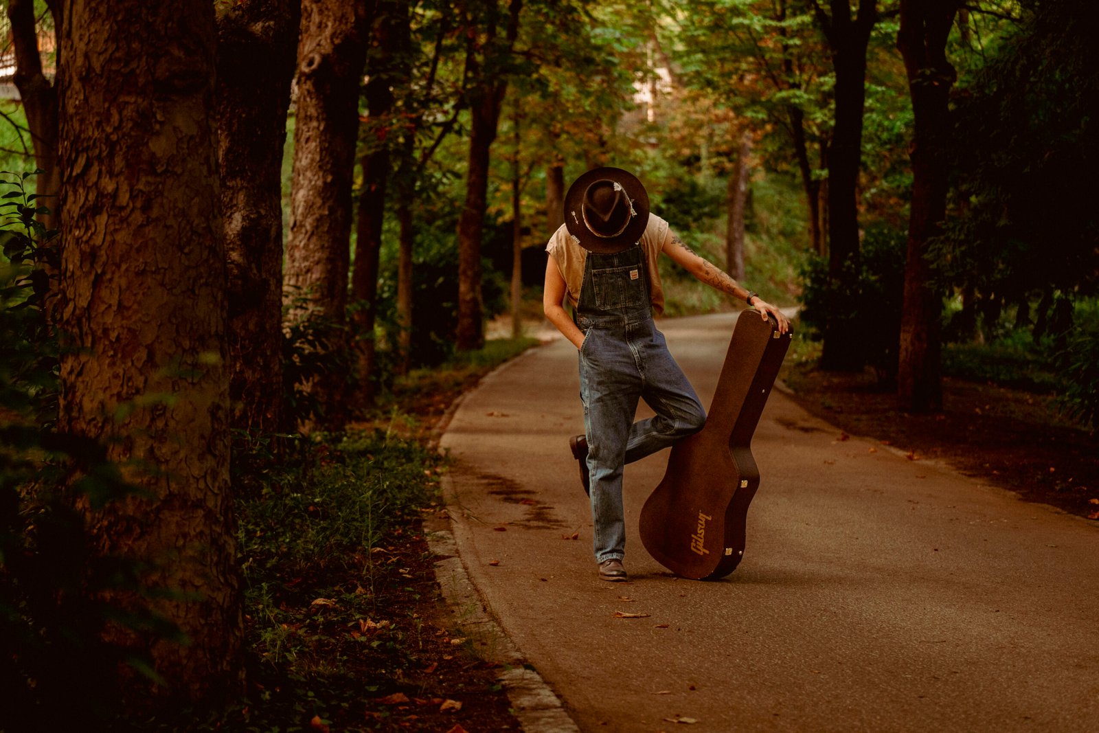 Musico con funda de instrumento en camino del bosque